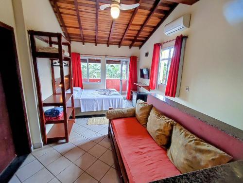 a living room with a red couch and a bed at Pousada Casa na Praia in Ubatuba