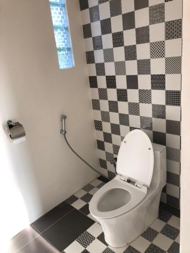 a bathroom with a toilet with a checkered wall at OUTSIDE bungalow in Sekongkang