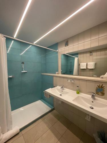 ein Badezimmer mit einer Badewanne, einem Waschbecken und einem Spiegel in der Unterkunft Restaurant-Pension Dorfwirt in Bad Kleinkirchheim