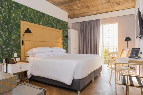 a bedroom with a large bed and a desk with a laptop at Faranda Collection Barranquilla, a member of Radisson Individuals in Barranquilla