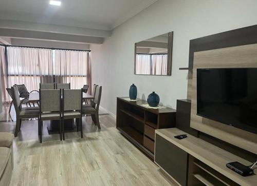 a living room with a television and a dining room at Apartamento na Avenida próximo das Termas in Piratuba