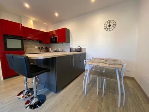 une cuisine avec des placards rouges, une table et un tabouret dans l'établissement Jolie maison, jardin et parking, à Désertines