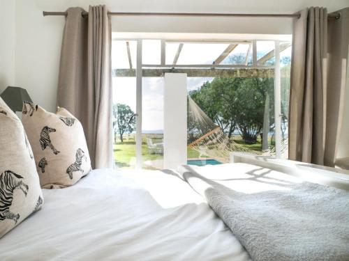 a bed with white sheets and pillows in front of a window at Land's End Private Game Reserve in Grahamstown