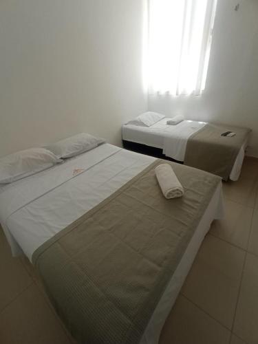 two beds in a white room with a window at Central Palace Hotel in Fortaleza