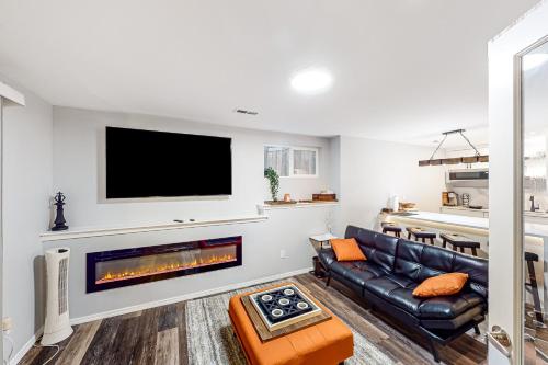 a living room with a black leather couch and a fireplace at Woodin-villa in Woodinville