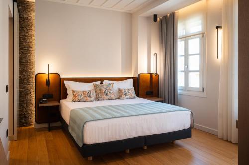 a bedroom with a bed with pillows and a window at Navria by Aetoma in Nafplio