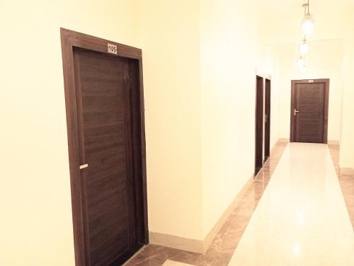 un couloir avec deux portes brunes et des murs blancs dans l'établissement Silver Oaks Inn, à Mathura