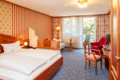 a hotel room with a bed and a desk and chairs at Parkhotel an der Therme in Bad Krozingen