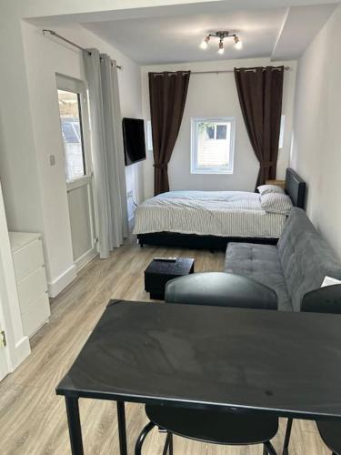 a living room with a couch and a bed at Large studio flat with garden in Teddington