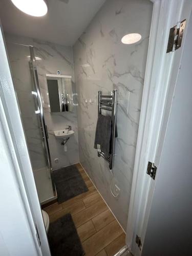 a white bathroom with a sink and a shower at Large studio flat with garden in Teddington