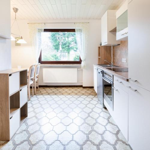 une cuisine avec des placards blancs et une fenêtre dans l'établissement Ferienwohnung Sonnenblume, 