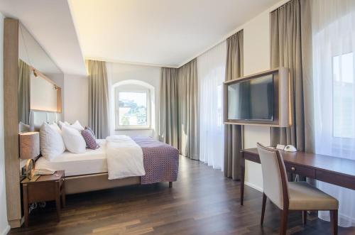 ein Hotelzimmer mit einem Bett, einem Schreibtisch und einem TV in der Unterkunft IMLAUER HOTEL PITTER Salzburg in Salzburg