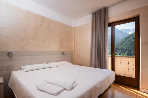 a bedroom with a bed and a large window at Hotel Vezza Alpine Lodge & Spa in Vezza dʼOglio