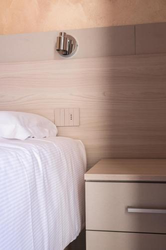 a bedroom with a bed and a nightstand with a white blanket at Hotel Vezza Alpine Lodge & Spa in Vezza dʼOglio
