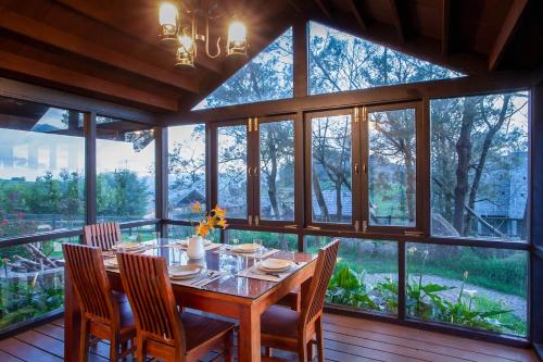 Un comedor con mesa y sillas y ventanas. en StayVista at Little Heaven with Breakfast, en Ooty