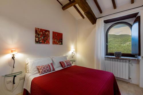 a bedroom with a red bed with a window at Relais L'Antico Convento in Galera