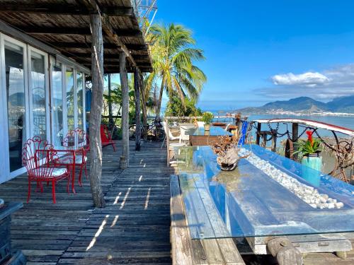 a resort deck with chairs and tables and the ocean at Lar da Lara in Ilhabela