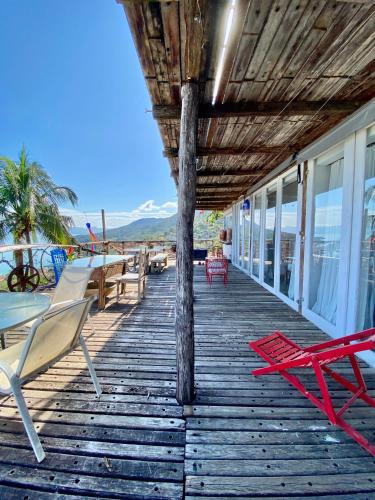 eine Holzterrasse mit Stühlen und Tischen am Strand in der Unterkunft Lar da Lara in Ilhabela