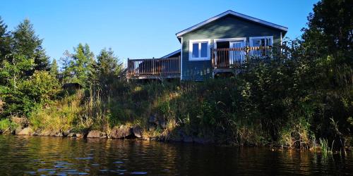 a house on a hill next to a river at Le Jasmin chalet complet Rivière Kayak Nature in Saint-Paulin