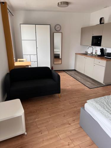 a living room with a black couch and a kitchen at City Appartement B Zur ewigen Lampe dritte Etage in Brühl