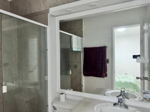 La salle de bains est pourvue d'un lavabo, d'un miroir et de toilettes. dans l'établissement Bel appartement sur l'île de Margarita, avec vue sur la mer, à Pampatar