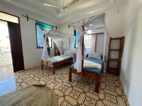 a bedroom with two beds and a canopy at Mauwa House in Paje