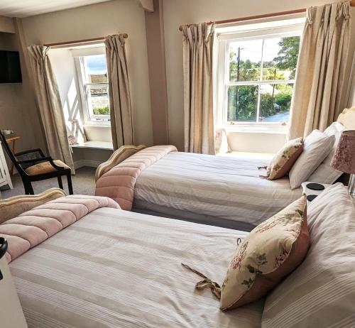 three beds in a room with two windows at Britannia House Vintage B&B Cornwall in Helston