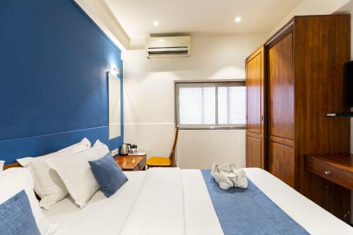 a bedroom with a large white bed with a blue wall at Hotel Q Deck Rooms - Vile Parle Station and Near to Mumbai Airport in Mumbai