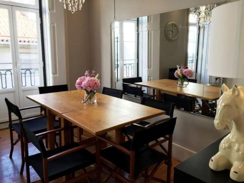 een eetkamer met 2 tafels en stoelen en bloemen bij SM2 Romantic HOME by the gardens PR Real & Bairro Alto in Lissabon