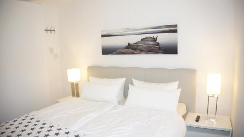 ein Schlafzimmer mit einem weißen Bett mit zwei Lampen in der Unterkunft Riff I in Norddeich