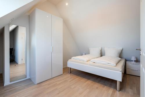 ノルトダイヒにあるJuistの白いベッドルーム(ベッド1台、鏡付)