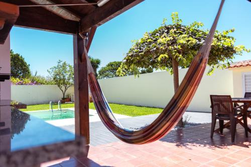 a hammock on a patio next to a pool at Retiro da Atafona Beach Pool House Yellow in Monte