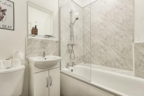 a white bathroom with a sink and a shower at Cosy Coastal Haven 1-Bedroom Apartment in Southend-On-Sea - Southend Stays in Southend-on-Sea