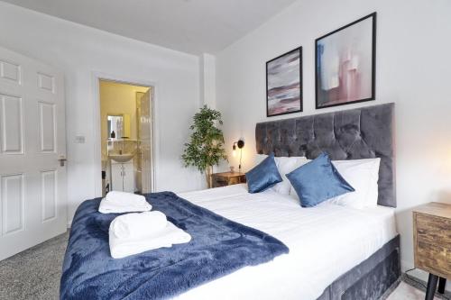 a bedroom with a large white bed with blue pillows at Cosy Coastal Haven 1-Bedroom Apartment in Southend-On-Sea - Southend Stays in Southend-on-Sea