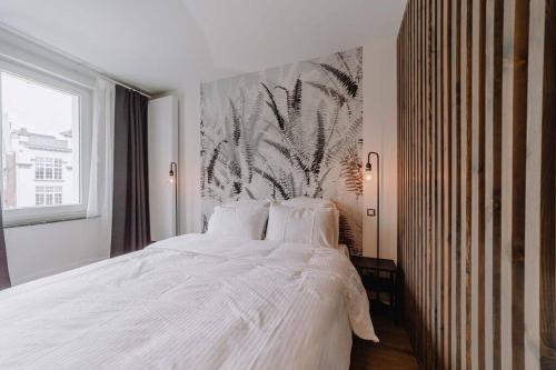 a bedroom with a white bed and a large window at Chimay : La Chambre Rouge de la Grand Place in Chimay