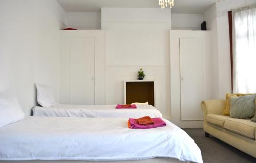 2 Betten in einem weißen Zimmer mit Sofa und Bettvisor in der Unterkunft 205 in Ilford