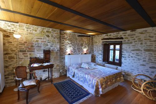 ein Schlafzimmer mit einem Bett in einem Zimmer mit Steinwänden in der Unterkunft Maison des Roses - Family Farm in Bossolasco