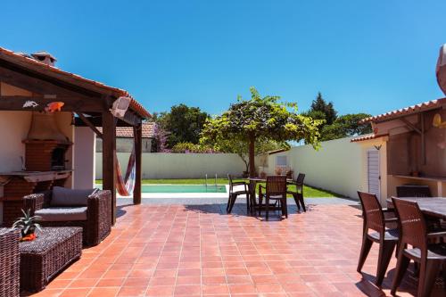 a patio with a table and chairs on a brick patio at Retiro da Atafona Beach Pool House Yellow in Monte