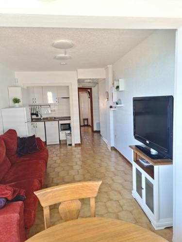 sala de estar con sofá rojo y TV de pantalla plana en Precioso apartamento en Cullera, con piscina junto a la playa, en Cullera