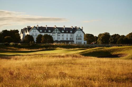 duży biały dom siedzący na szczycie pola golfowego w obiekcie Dornoch Station w mieście Dornoch