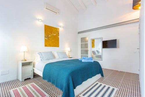 ein weißes Schlafzimmer mit einem großen Bett mit blauer Bettwäsche in der Unterkunft Bluehouse Portixol in Palma de Mallorca