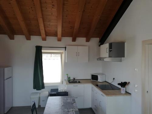 een keuken met witte kasten en een tafel en een raam bij Appartamento Veses in Santa Giustina