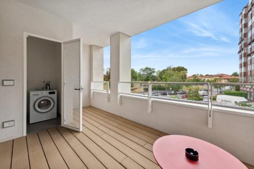 a balcony with a washing machine and a pink table at limehome Milan via Stresa in Milan