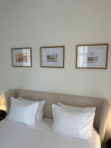 een bed met witte kussens en twee foto's aan de muur bij Golden Lisbon Hotel in Lissabon