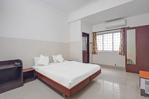 a bedroom with a bed and a desk and a window at Chennai Guest House in Chennai