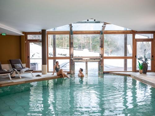 two people sitting in a swimming pool at Falkensteiner Hotel Antholz - Adults only in Anterselva di Mezzo