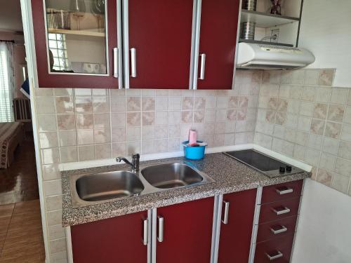 a kitchen with red cabinets and a sink at Apartments Gojka Miocevic in Biograd na Moru