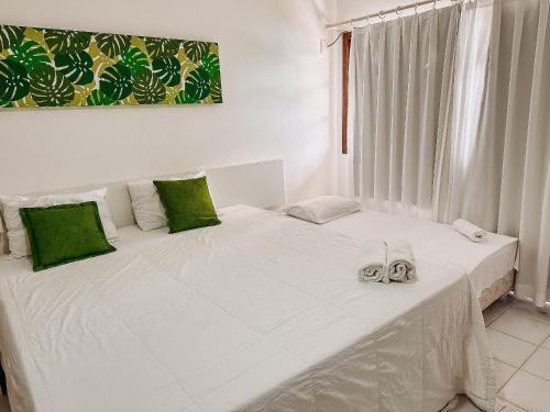 uma cama branca com um par de sapatos em A 200m da praia de Taperapuã, (Axé Mói) 2 suítes piscina, sauna, portaria 24hrs internet privativa 300MBPS em Porto Seguro