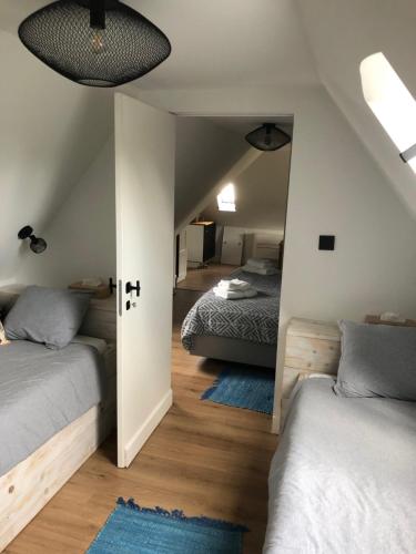 a attic bedroom with two beds and a hallway at Het mezennest in Zottegem