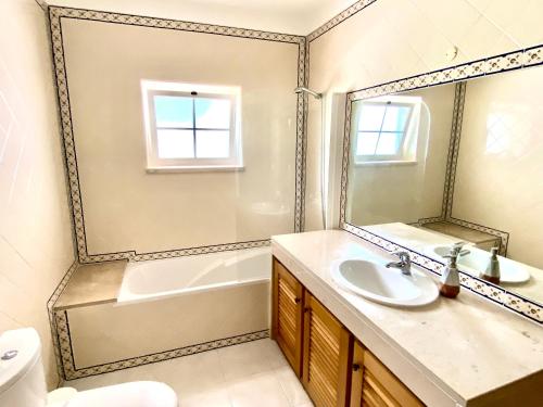 ein Badezimmer mit Waschbecken, Badewanne und Spiegel in der Unterkunft Villa in Praia D'el Rey, Beach & Golf Resort in Casal da Lagoa Seca
